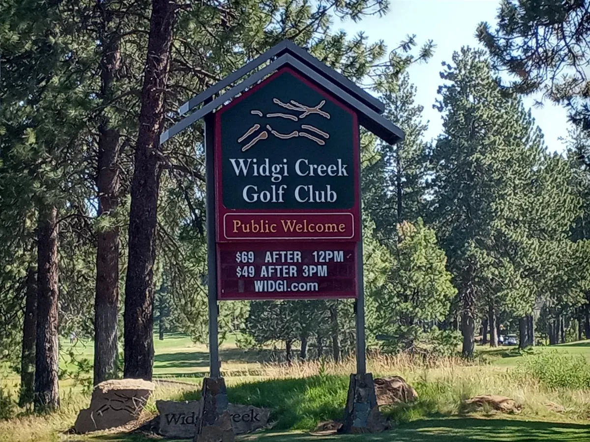 A view of the Widgi Creek Golf Club sign nestled among surrounding trees, complete with pricing details. The image conveys a sense of community and leisure, set against a backdrop of the lush outdoors.