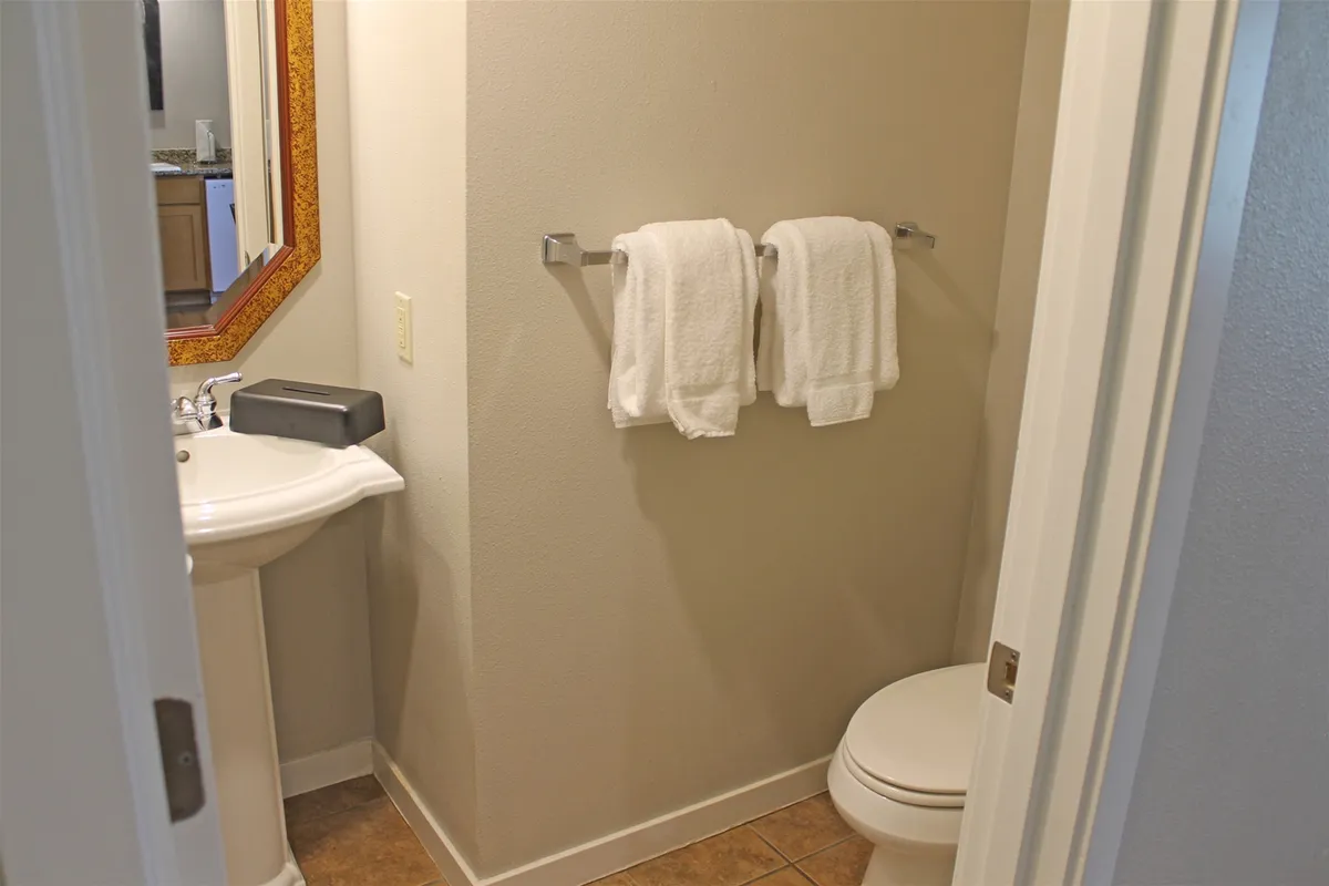A bright and modern bathroom featuring a sink with a large mirror, neatly arranged towels, and a fresh, inviting atmosphere—perfect for morning routines or a relaxing evening wind-down.